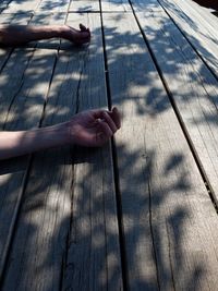 Cropped hands of man lying on floorboard