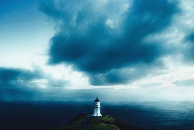 Lighthouse amidst buildings against sky