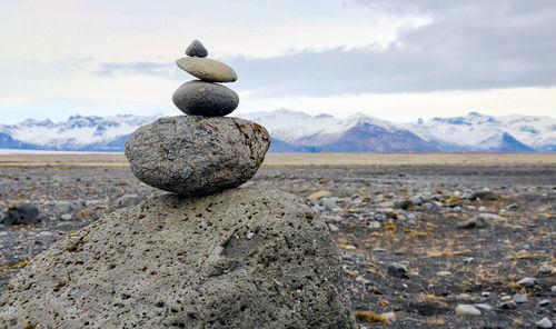 Rocks on landscape against cloudy sky