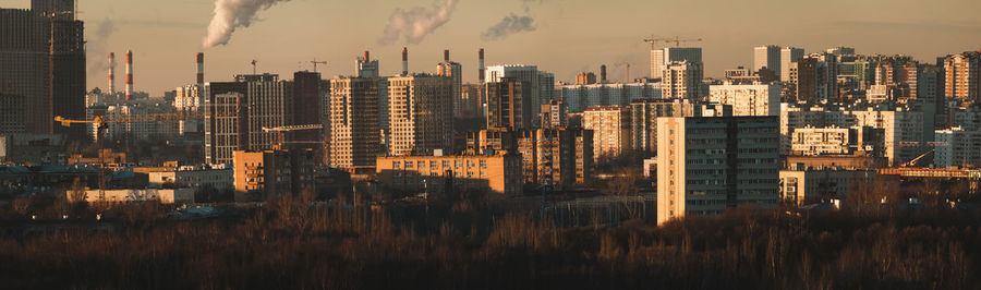 Urban skyline with smoking plant chimneys, cityscape panorama