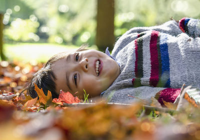 Close-up of smiling boy lying outdoors