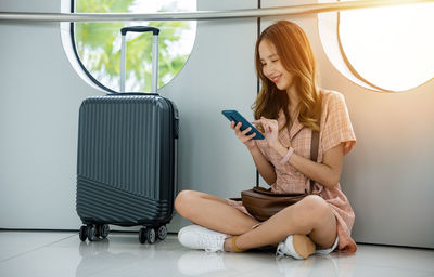 Side view of young woman using mobile phone while sitting at home