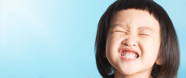 Close-up portrait of happy boy against blue background