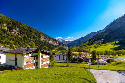 Plants and buildings against mountains and blue sky