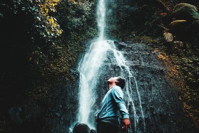 Man looking at waterfall in forest