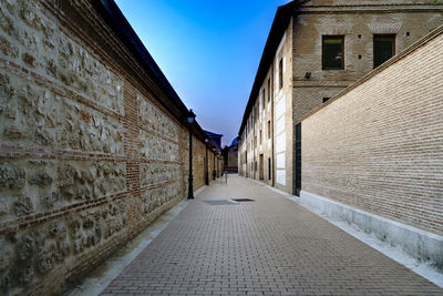 Walkway amidst buildings against sky