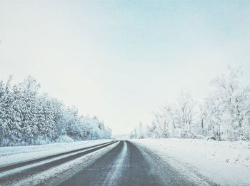 Road amidst trees against sky during winter