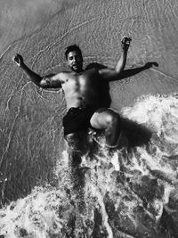 Full length of shirtless man lying in sea