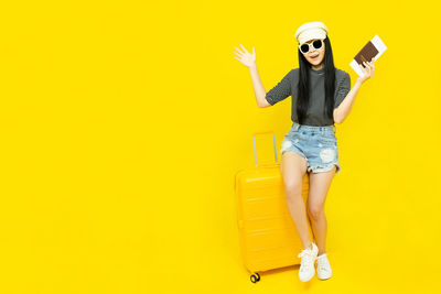 Woman wearing sunglasses against yellow background