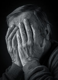 Elderly man covered his face with his hands, black and white portrait