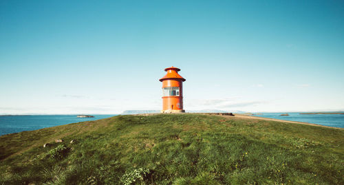 Lighthouse by sea against sky