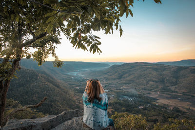 Rear view of woman photographing mountains against sky