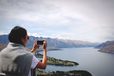 Rear view of man photographing while standing on lake