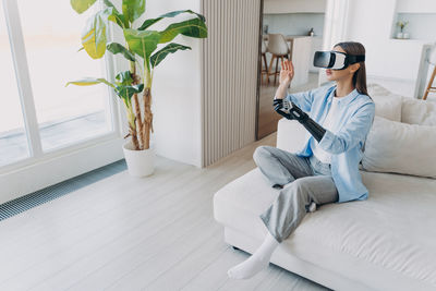 Portrait of woman using mobile phone while sitting on sofa at home