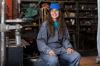 Smiling woman in uniform sitting in workshop