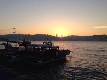 Boats sailing in sea at sunset