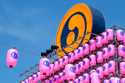 Low angle view of japanese lanterns and symbol against blue sky