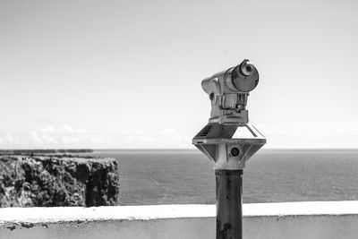 Binoculars at observation point by sea against clear sky