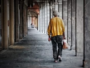 Rear view of man walking in corridor of building