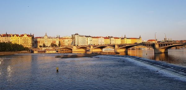 Bridge over river in city against clear sky