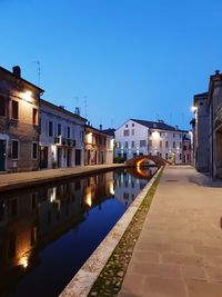 Canal amidst buildings in city against clear blue sky