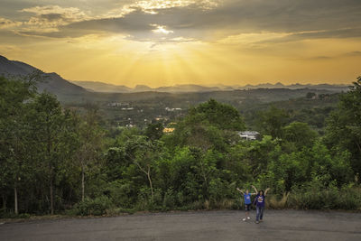 Rear view of man on mountain against sky during sunset