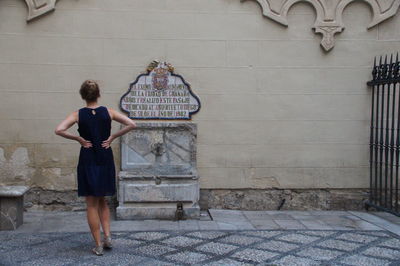 Full length rear view of woman standing against building