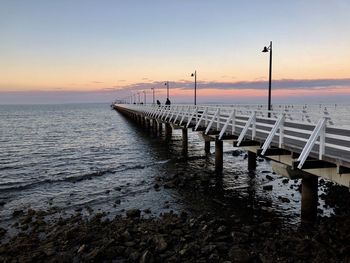 Pier over sea against sky during sunset