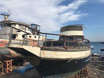 Abandoned boat moored on beach against sky