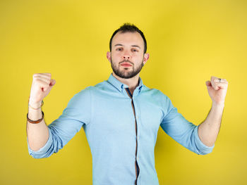 Portrait of young man standing against yellow background