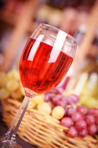Close-up of red wine in wineglass by grapes on table