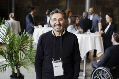 Smiling businessman wearing id card standing in conference center