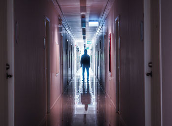 Rear view of man walking in corridor of building