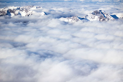 High angle view of mountains breaking through sea of clouds