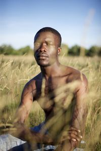 Portrait of young man sitting on field