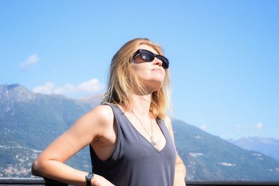 Portrait of young woman wearing sunglasses against mountain