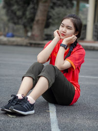 Young woman looking away while sitting on mobile phone in city