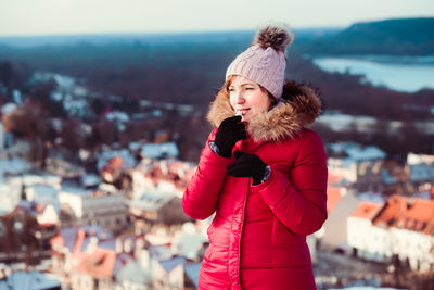 Young woman standing against sea during winter