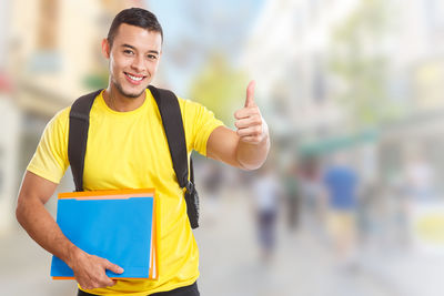 Portrait of young man holding yellow while standing outdoors