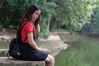 Side view of young woman using mobile phone in water