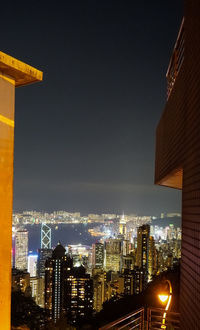 Illuminated buildings in city against clear sky at night