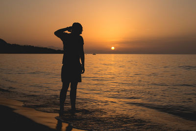 Silhouette man on beach against sky during sunset