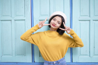 Smiling young woman standing against door