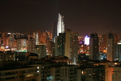 Illuminated cityscape against sky at night