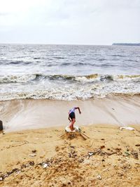 Man falling at beach against sky