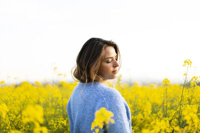 Beautiful woman standing on field against yellow sky