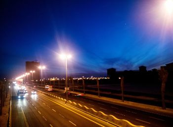 Cars on illuminated road against sky at night