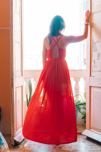 Rear view of woman standing by window at home