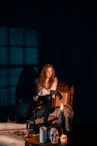 Young woman sitting on seat in illuminated room