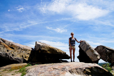 Low angle view of woman standing on rock against sky